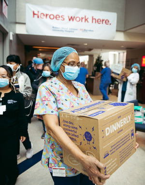 A nurse holds Dinnerly meal kit as others line up to receive theirs. 